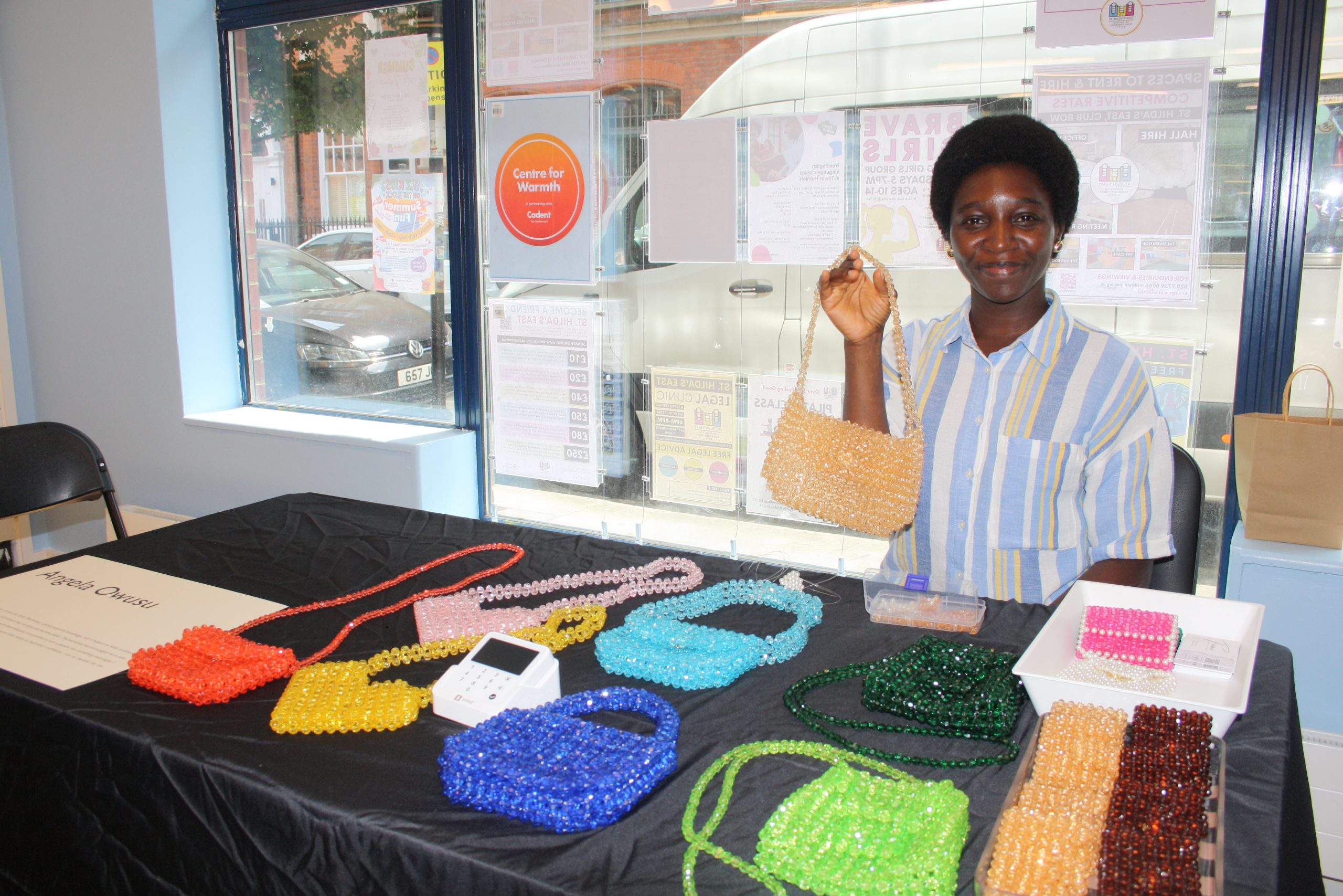lady sitting behind table holding beaded bags
